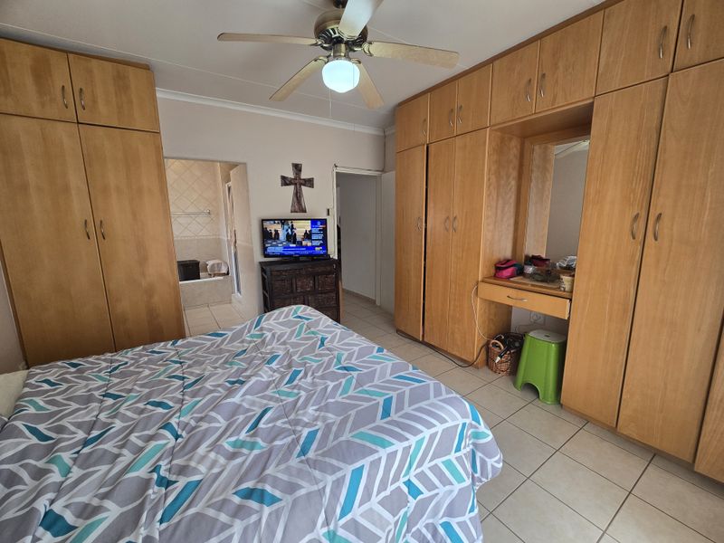 Bedroom featuring extensive built-in wooden cabinetry, a ceiling fan, tiled flooring, and direct access to an en-suite bathroom.