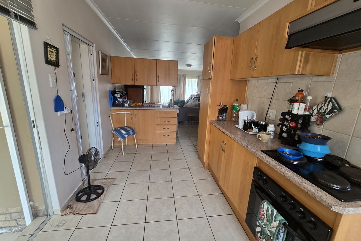 A functional kitchen featuring light wood cabinetry, laminate countertops, tiled flooring, and integrated cooking appliances, offering a practical layout for daily use.