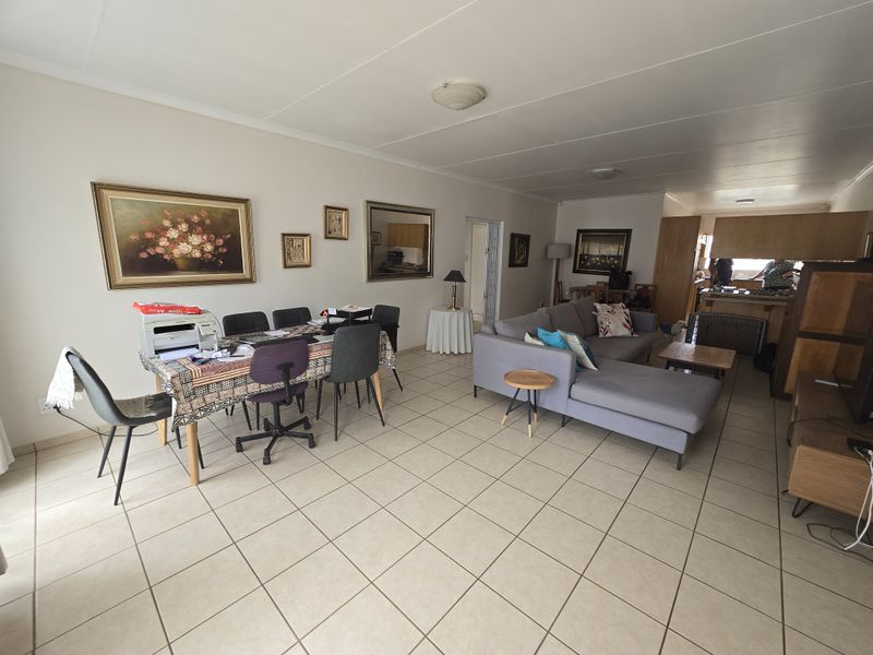 Spacious open-plan living and dining area featuring neutral ceramic floor tiles and direct access to the kitchen space.