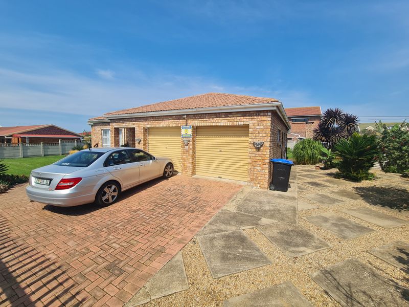 A well-maintained brick-faced house featuring a double garage, paved driveway, and established garden area.