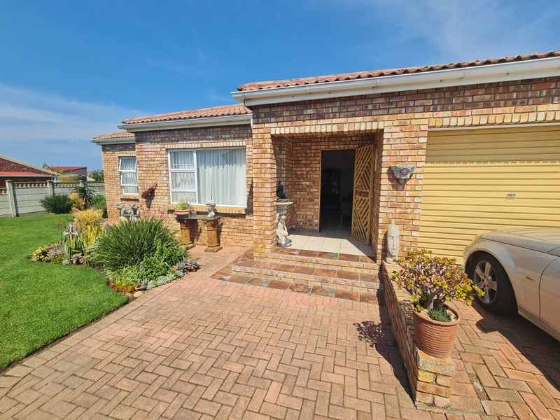 Front elevation of a face brick house featuring a paved driveway, single garage, and a covered entrance porch with tiled steps.
