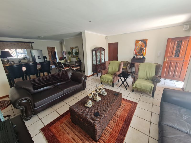 Spacious open-plan living area featuring tiled flooring, neutral walls, and integrated kitchen space, offering a versatile layout for family living and entertaining.