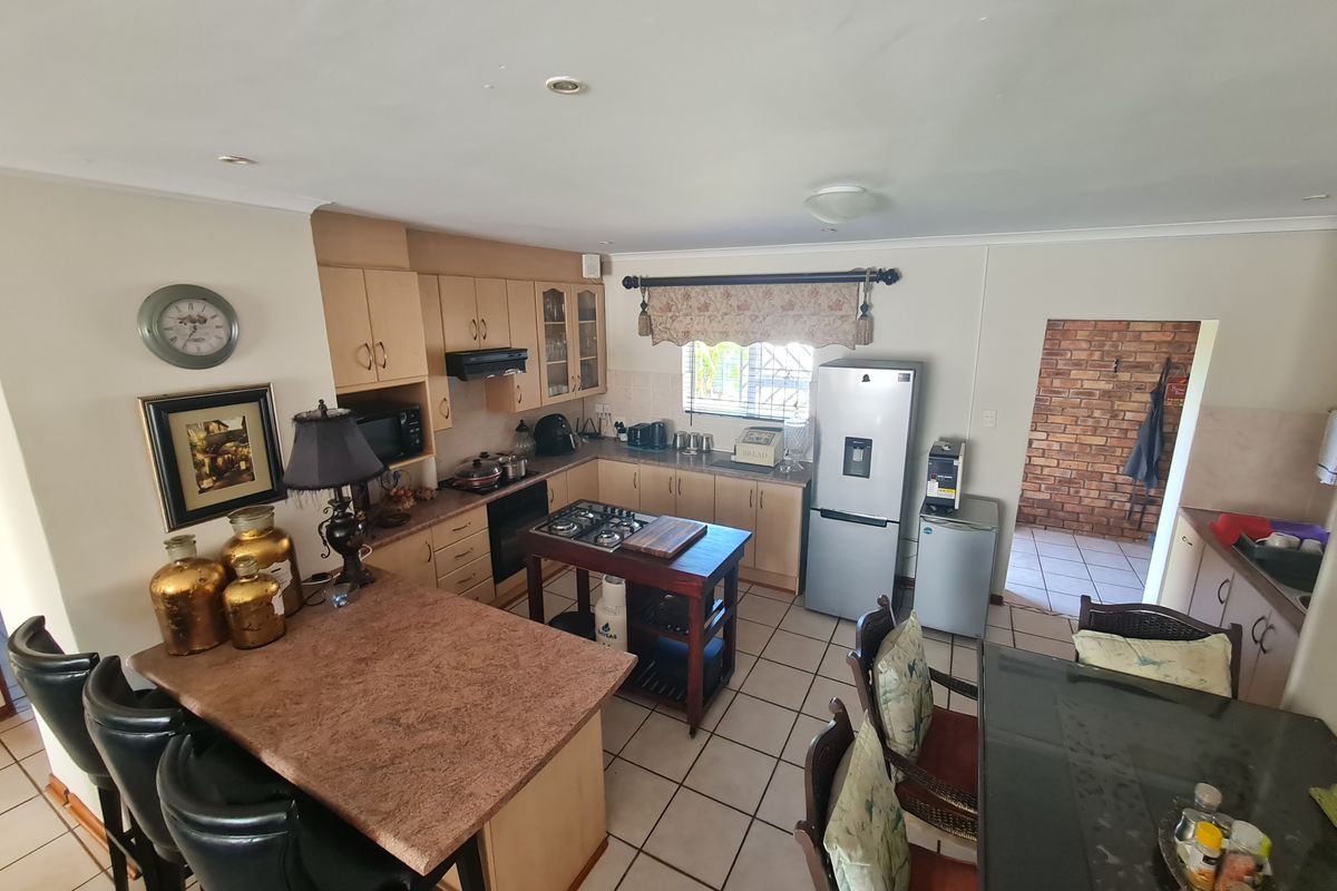 A functional kitchen featuring built-in cabinetry, a gas hob, breakfast bar, and ceramic tiled flooring, offering a practical layout for daily meal preparation.