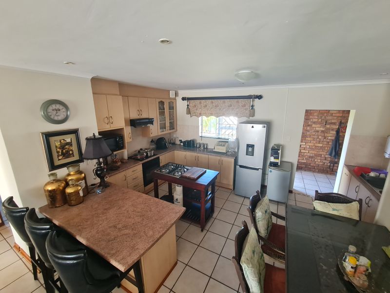 A functional kitchen featuring built-in cabinetry, a gas hob, breakfast bar, and ceramic tiled flooring, offering a practical layout for daily meal preparation.