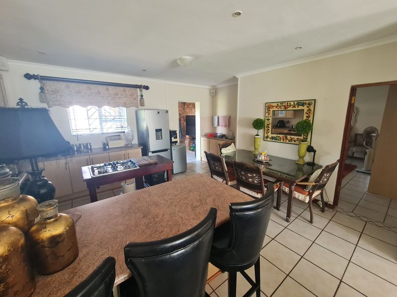 Open plan kitchen and dining area featuring tiled flooring, built-in cabinetry, and a breakfast counter, offering a functional layout for daily living.