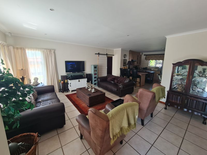 Spacious open-plan living area featuring tiled flooring, recessed lighting, and a seamless flow into the kitchen with a central island and cabinetry.