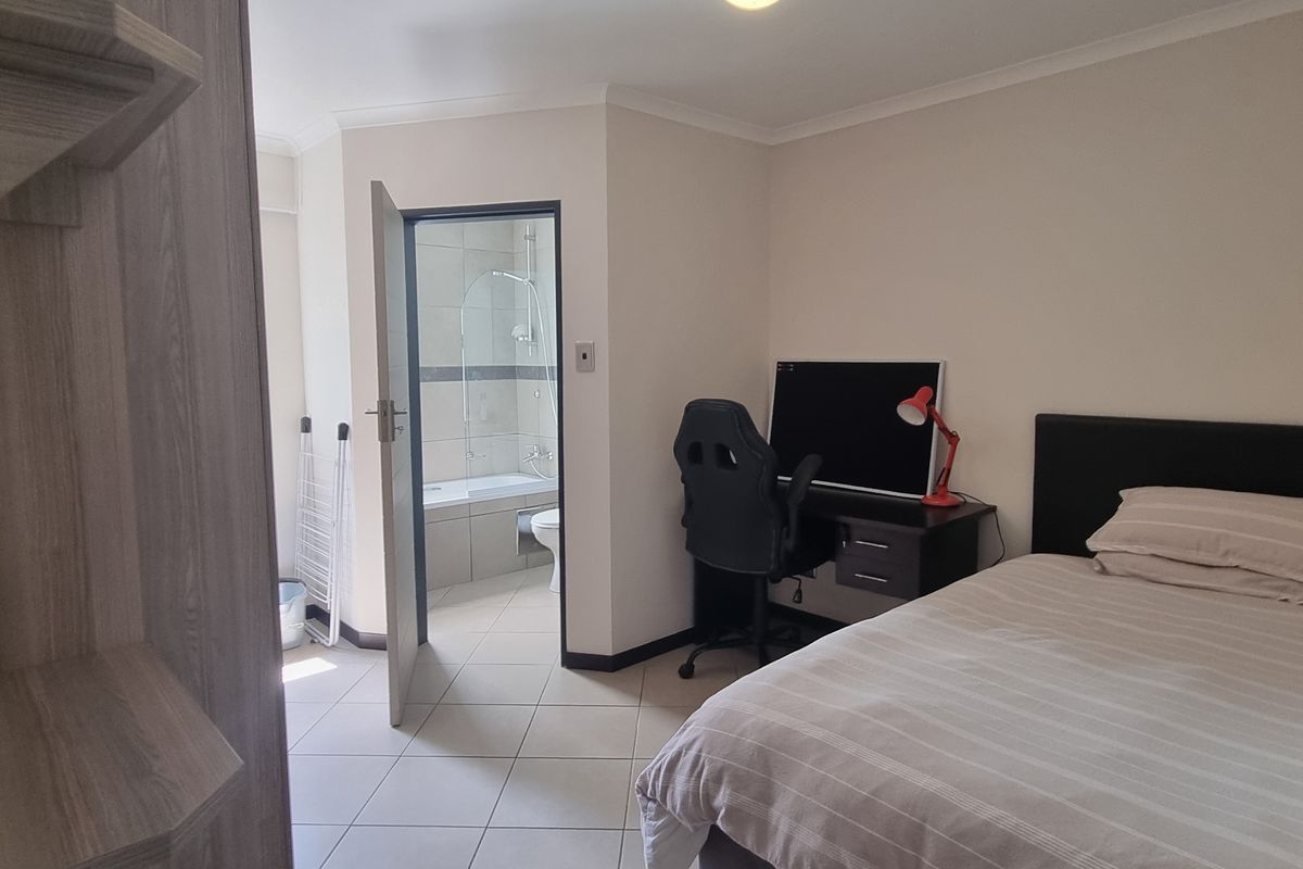 A well-maintained bedroom featuring tiled flooring, a built-in wardrobe, and direct access to an en-suite bathroom.