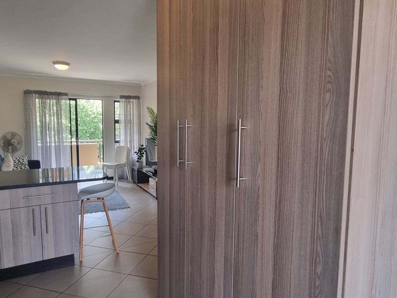Open-plan living area featuring a modern kitchen with granite countertops, built-in cabinetry, and direct access to a balcony through sliding glass doors.