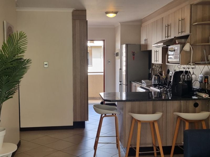 Open-plan living area featuring a modern kitchen with granite countertops, built-in cabinetry, and a breakfast nook, leading to an outdoor balcony.