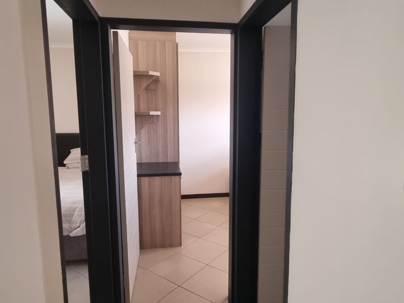 A view through a doorway into a bedroom area featuring tiled flooring and built-in wooden cabinetry.