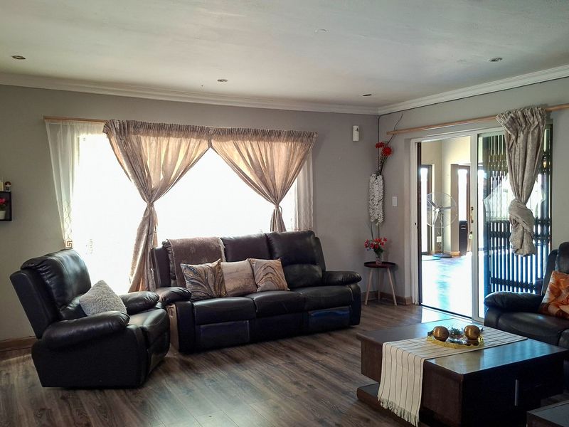 A spacious living room featuring modern laminate flooring, recessed lighting, and large sliding glass doors that provide access to the outdoor area.
