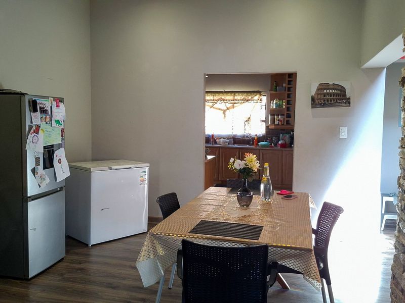 Open plan dining area featuring a stone-clad feature wall and laminate flooring, with a convenient pass-through window connecting to the kitchen space.