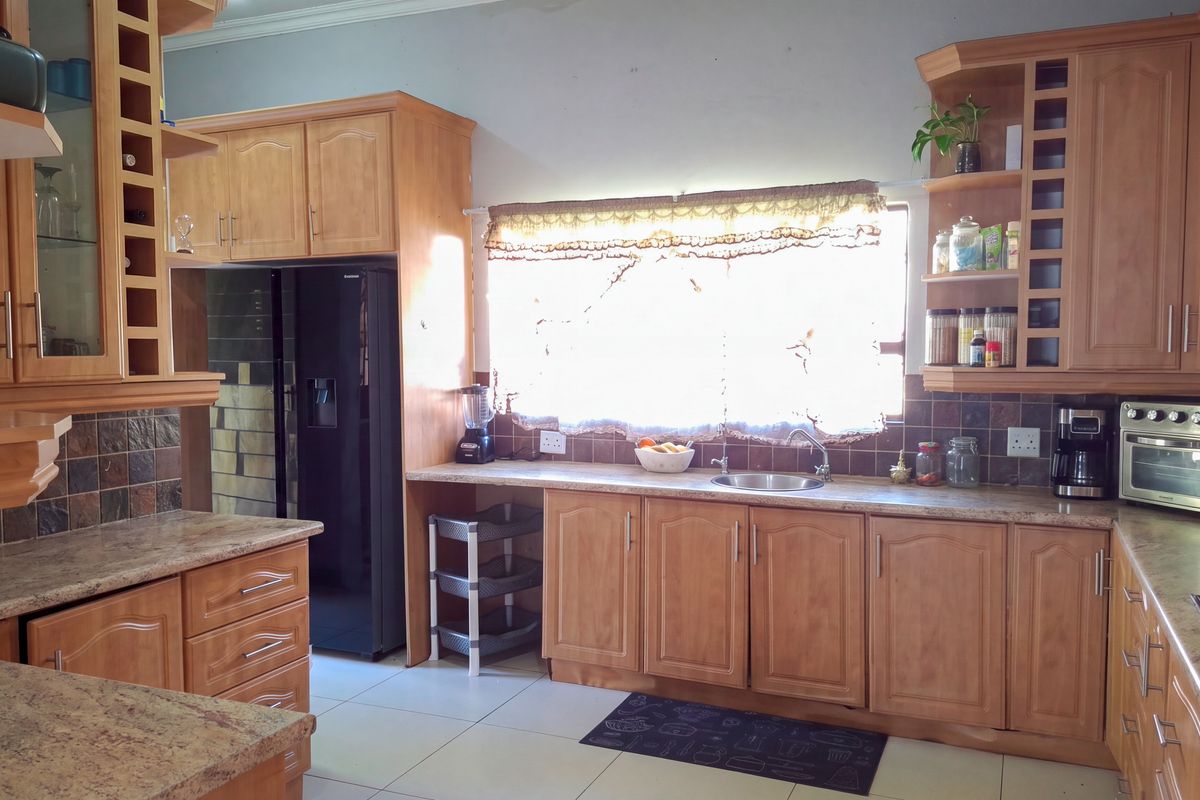 A functional kitchen featuring warm-toned wooden cabinetry, granite countertops, a built-in oven, and a tiled backsplash with ample storage space.
