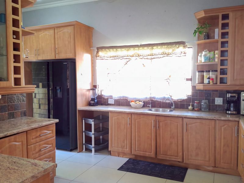 A functional kitchen featuring warm-toned wooden cabinetry, granite countertops, a built-in oven, and a tiled backsplash with ample storage space.