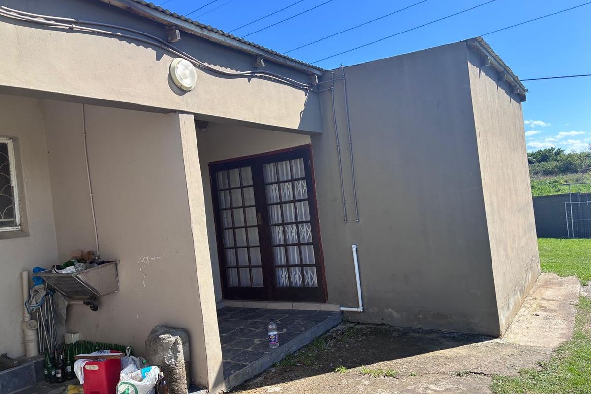 Rear exterior view of the property featuring a covered patio area, double glass doors, and exposed exterior plumbing and electrical conduits.