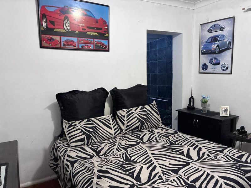 A bedroom featuring white walls, coving, and an adjacent tiled shower enclosure.