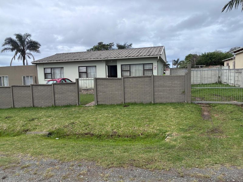 Front exterior view of a single-story house featuring a metal roof, aluminium windows, and a fully enclosed yard with a precast concrete boundary wall.