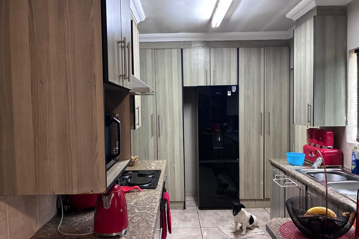 A functional kitchen featuring wood-look cabinetry, laminate countertops, integrated appliances, and tiled flooring, offering a practical layout for daily meal preparation.