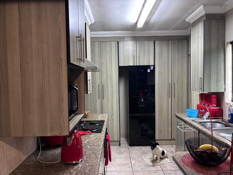 A functional kitchen featuring wood-look cabinetry, laminate countertops, integrated appliances, and tiled flooring, offering a practical layout for daily meal preparation.