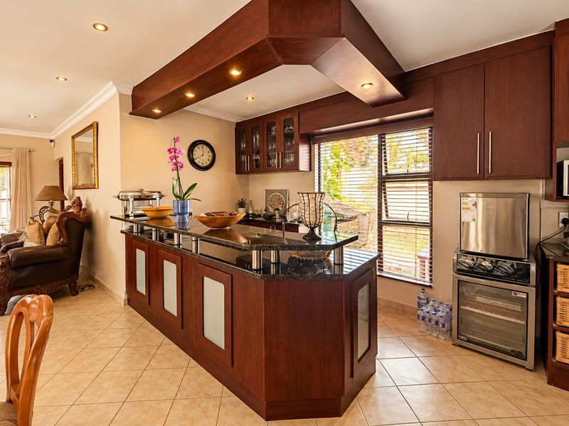 Open-plan living area featuring a custom built-in bar with granite countertops, dark wood cabinetry, and integrated lighting, seamlessly connecting to the adjacent lounge space.
