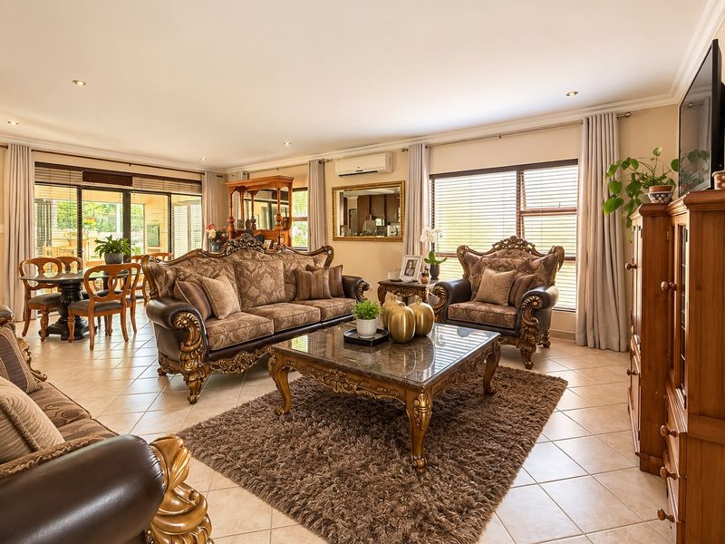 Spacious open-plan living and dining area featuring tiled flooring, recessed lighting, split-system air conditioning, and large sliding doors leading to the outdoor patio.