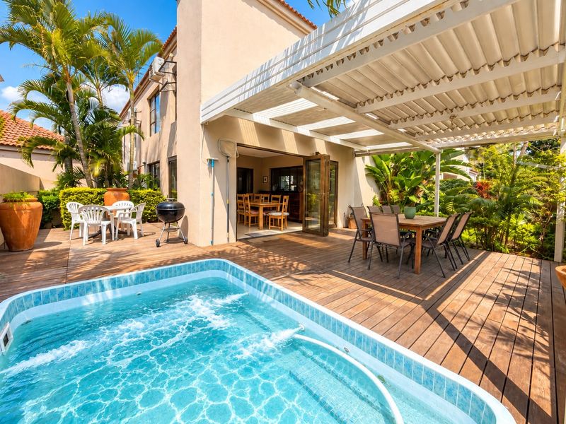 Outdoor entertainment area featuring a swimming pool, timber decking, and a covered pergola, seamlessly connected to the interior living space via bi-fold doors.