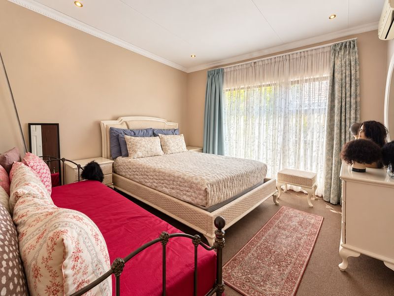 A well-lit bedroom featuring neutral wall tones, recessed ceiling lighting, crown molding, and a large sliding glass door providing natural light.