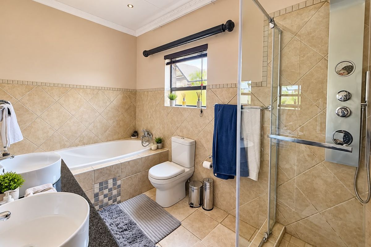 A well-appointed bathroom featuring a dual vanity with granite countertop, a built-in bathtub, and a glass-enclosed shower with integrated body jets.