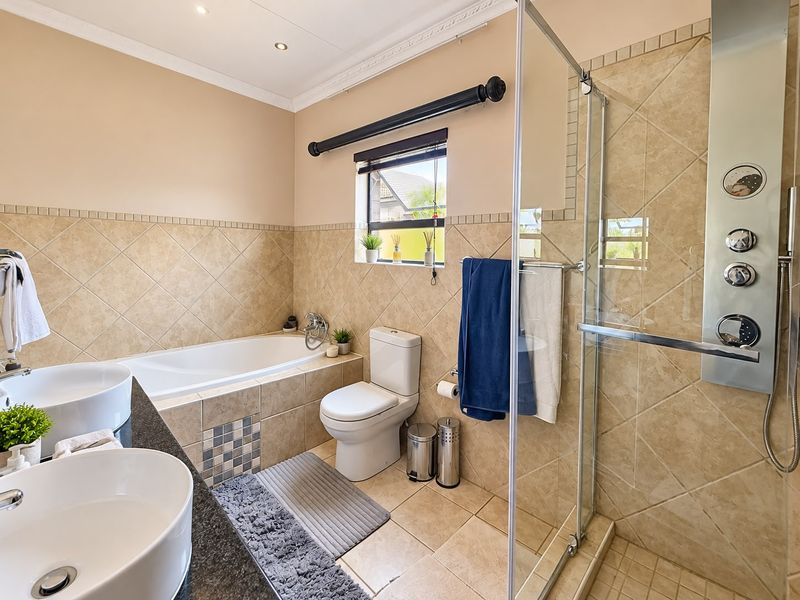 A well-appointed bathroom featuring a dual vanity with granite countertop, a built-in bathtub, and a glass-enclosed shower with integrated body jets.