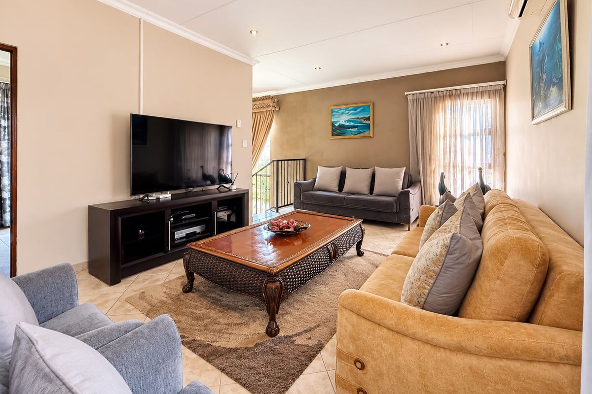 A comfortable living room featuring tiled flooring, recessed downlights, and an integrated air conditioning unit, with an open transition to the staircase area.