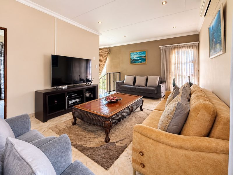 A comfortable living room featuring tiled flooring, recessed downlights, and an integrated air conditioning unit, with an open transition to the staircase area.