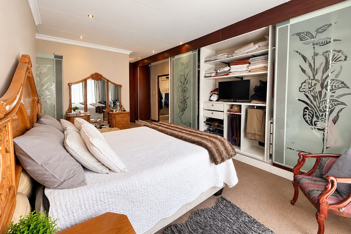Spacious bedroom featuring extensive built-in cupboards with sliding glass doors, recessed lighting, and neutral carpeting.
