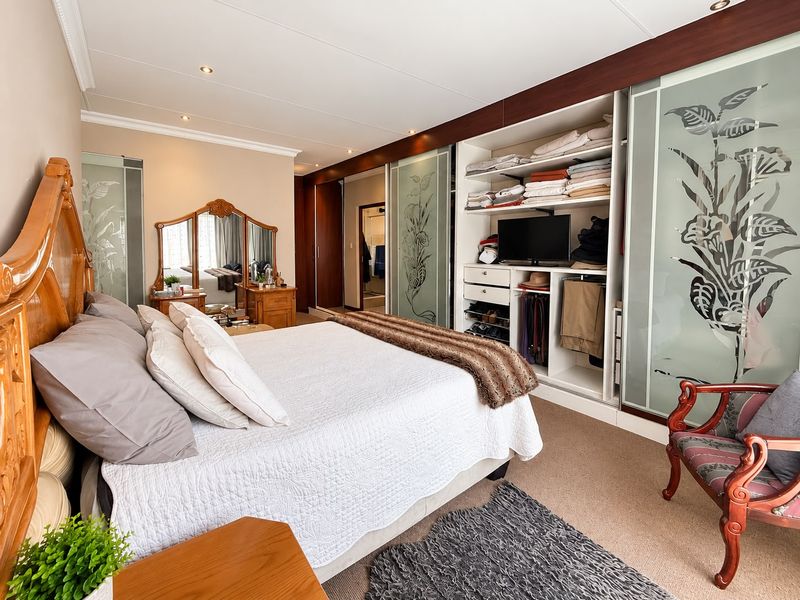 Spacious bedroom featuring extensive built-in cupboards with sliding glass doors, recessed lighting, and neutral carpeting.