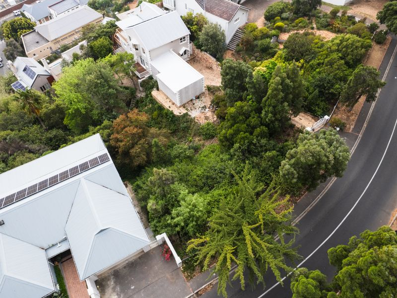 Aerial view of a residential property featuring mature landscaping, a paved driveway, and a building with solar panels installed on the roof.