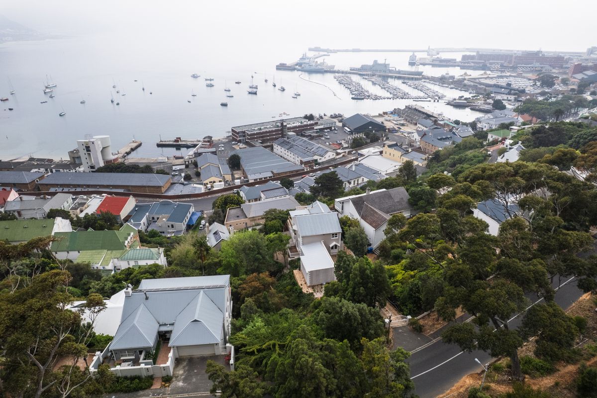An elevated aerial view of a coastal residential area overlooking a harbour and marina, showcasing the surrounding landscape and neighbourhood layout.