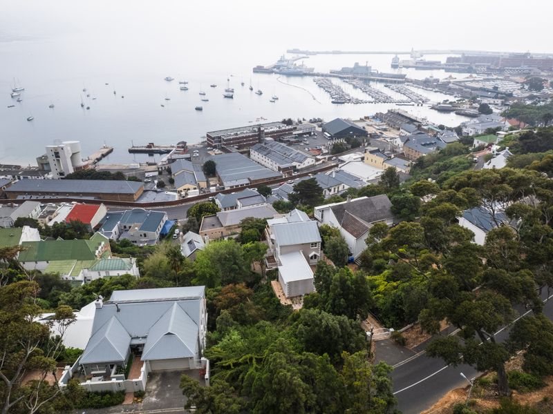 An elevated aerial view of a coastal residential area overlooking a harbour and marina, showcasing the surrounding landscape and neighbourhood layout.