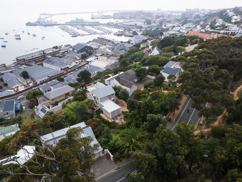 An elevated aerial view of a residential neighborhood situated on a hillside overlooking the harbor and coastal area.