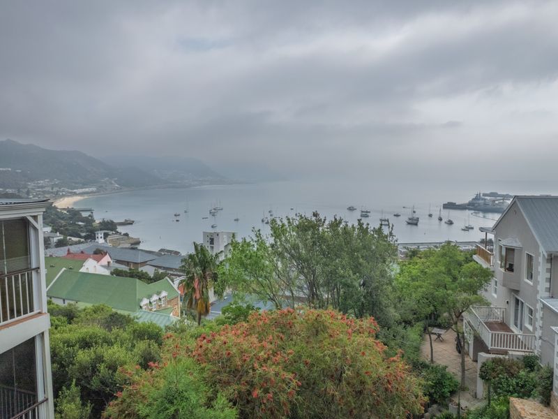 A scenic elevated view overlooking the bay, harbour, and surrounding coastal landscape under an overcast sky.