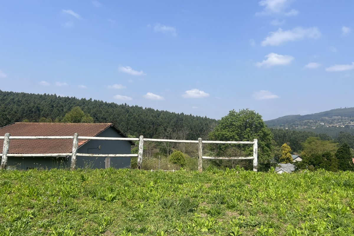 A scenic view of the surrounding landscape featuring a post and rail fence and a glimpse of a nearby structure.