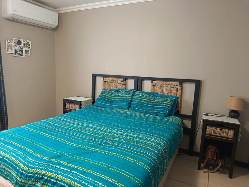 A functional bedroom featuring tiled flooring, crown molding, and a wall-mounted split-system air conditioning unit.