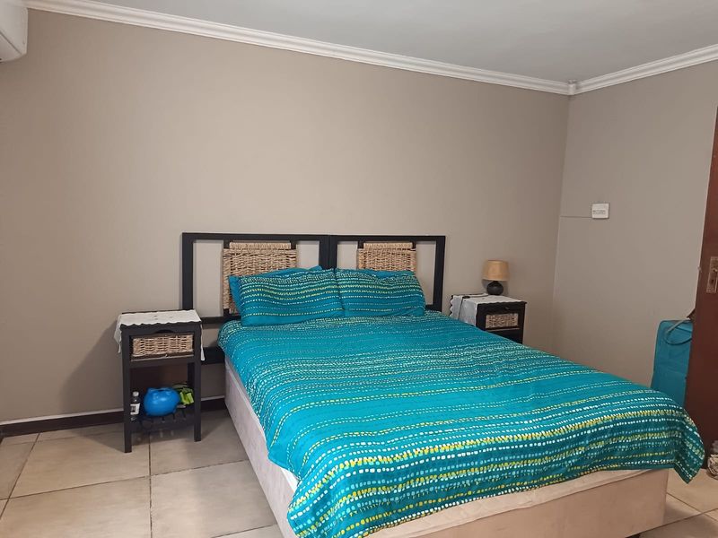 A functional bedroom featuring tiled flooring, coved cornicing, and a wall-mounted air conditioning unit.