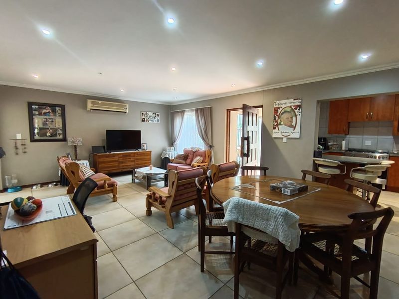 Spacious open-plan living, dining, and kitchen area featuring tiled flooring, recessed lighting, and a functional kitchen layout with built-in cabinetry and appliances.