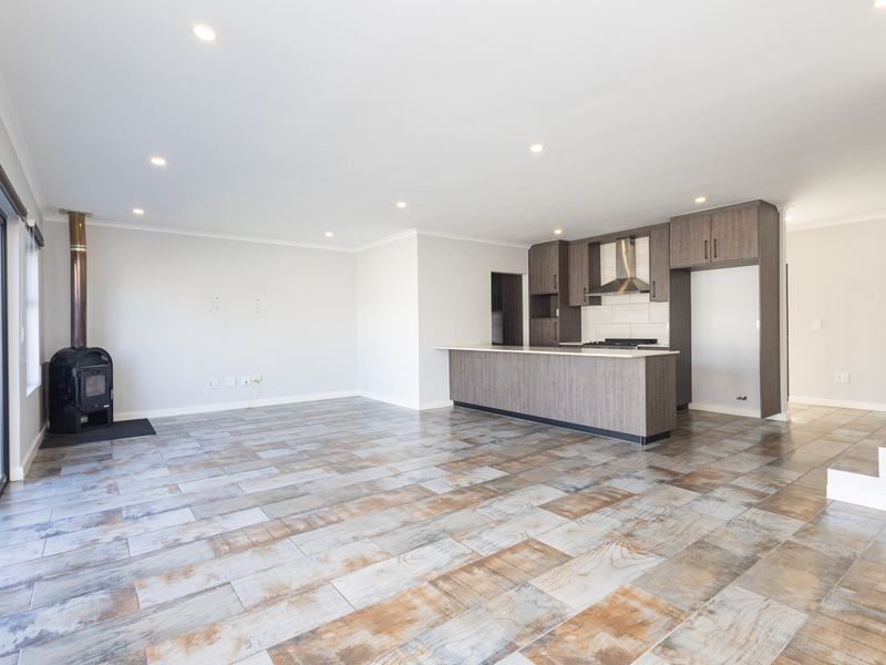 Spacious open-plan living area featuring a modern kitchen with island, wood-burning fireplace, and large sliding doors leading to the exterior.