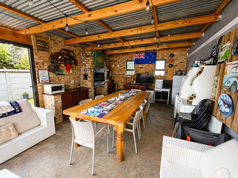 Spacious covered patio featuring exposed timber rafters, face brick walls, and a built-in braai, ideal for outdoor entertaining.