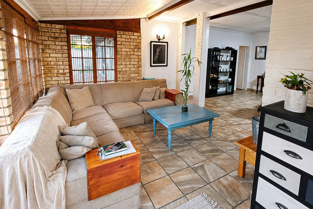A living room featuring exposed brick walls, tiled flooring, and a textured ceiling, offering a rustic aesthetic with potential for modern updates.
