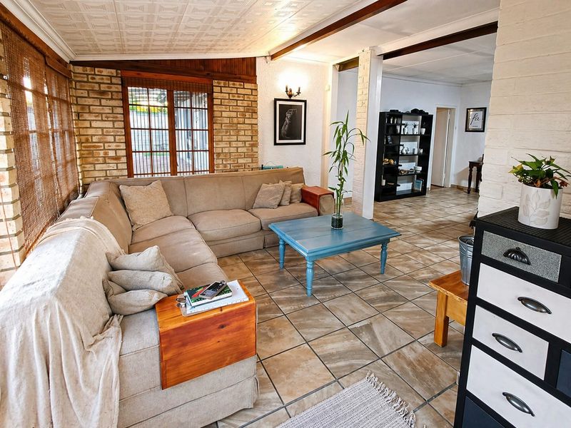 A living room featuring exposed brick walls, tiled flooring, and a textured ceiling, offering a rustic aesthetic with potential for modern updates.