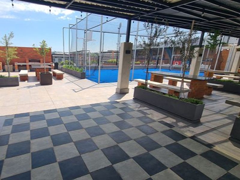 Outdoor sports facility featuring a covered patio area with built-in braai and a dedicated sports court with perimeter netting.
