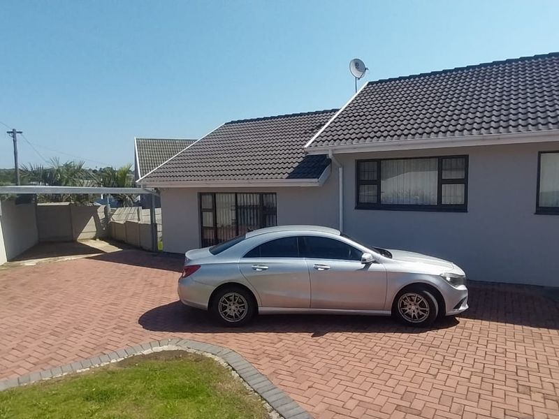 Front exterior view of the house featuring a paved driveway, carport, and secure boundary wall with a sliding gate.