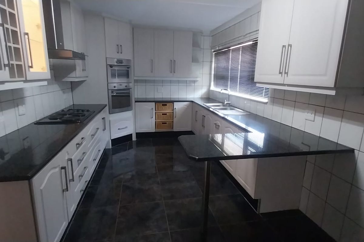 A well-maintained kitchen featuring dark granite countertops, built-in appliances, ample cabinetry, and tiled finishes throughout.