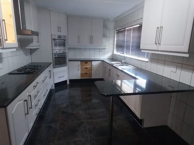 A well-maintained kitchen featuring dark granite countertops, built-in appliances, ample cabinetry, and tiled finishes throughout.